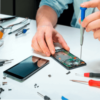 Person repairing a Samsung phone with a screwdriver on a workbench surrounded by tools.